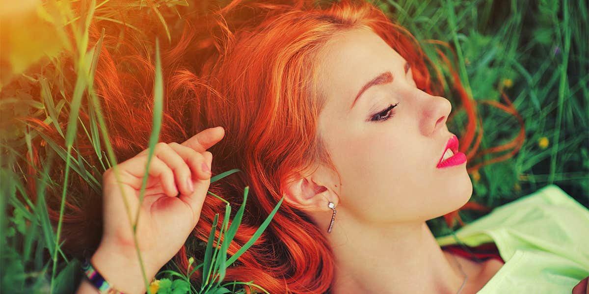 red haired woman laying in grass