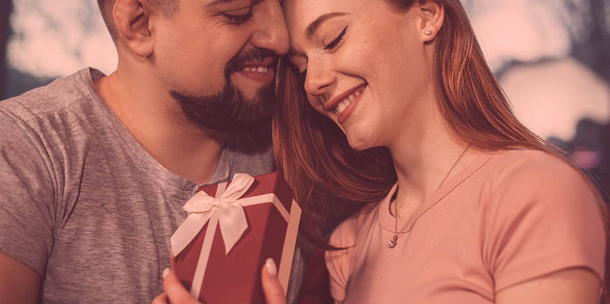 woman opening up a gift, with a man by her side