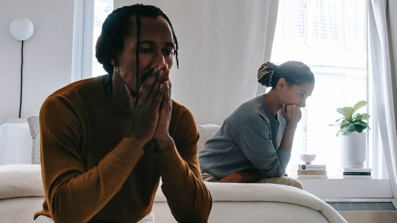 man and woman facing away from each other sitting on a bed