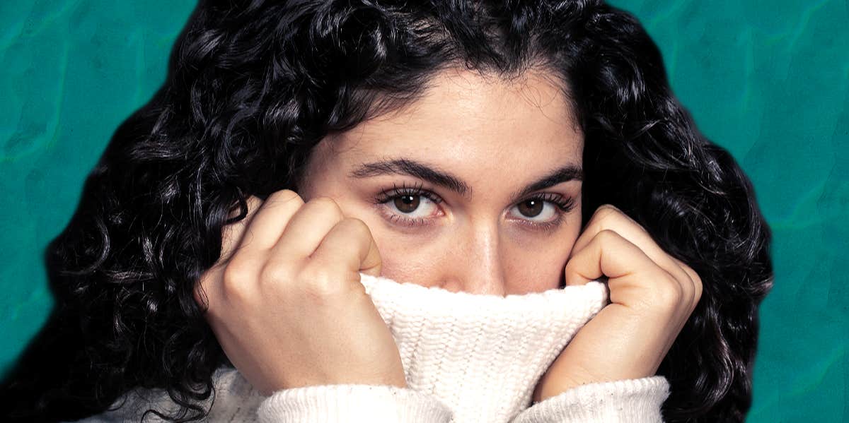 woman covering face with sweater