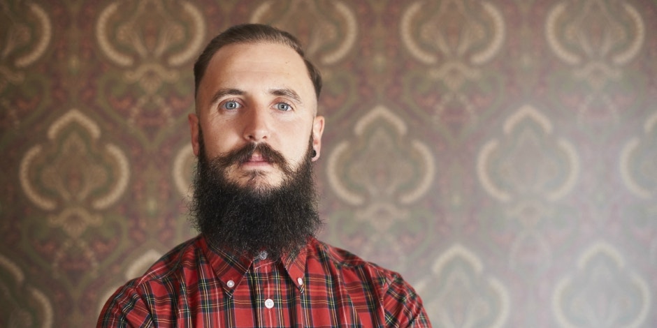 Man with a long, dark beard looking directly at camera