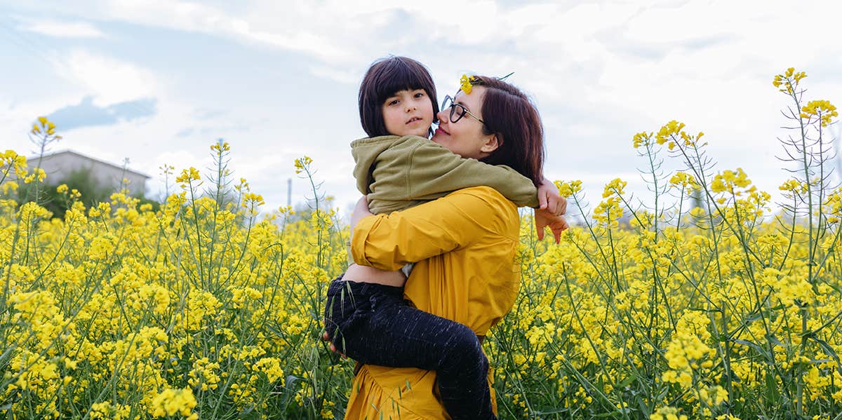 mother holding child in flower field
