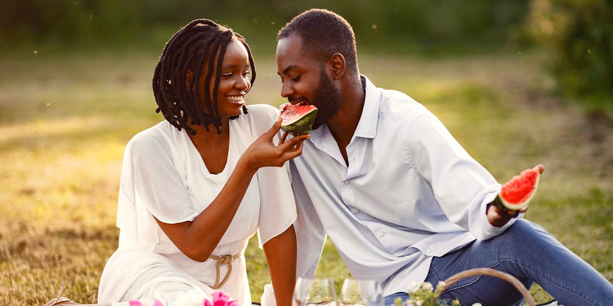wife feeding husband watermelon while enjoying picnic date
