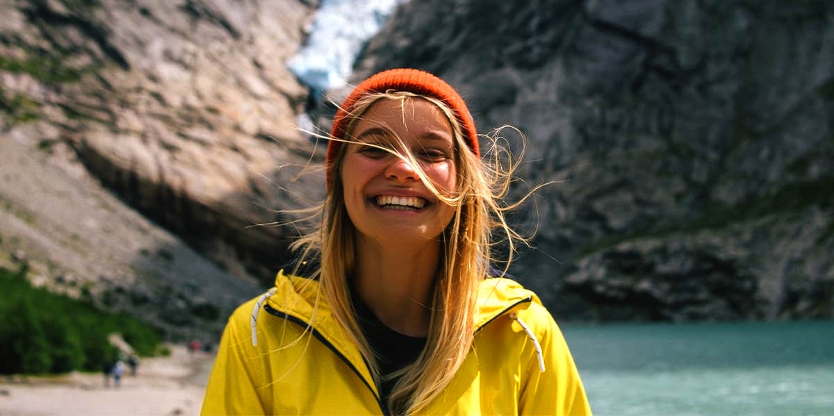 smiling woman wearing beanie and yellow jacket