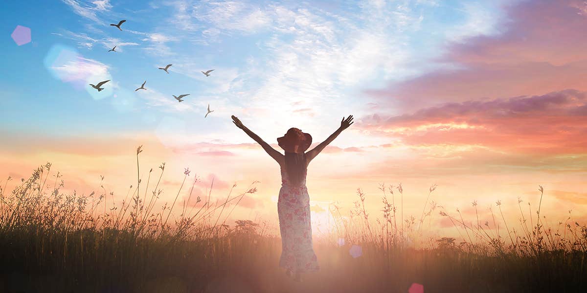 5 Rare Signs You're Spiritually Blessed girl in sunset with arms raised