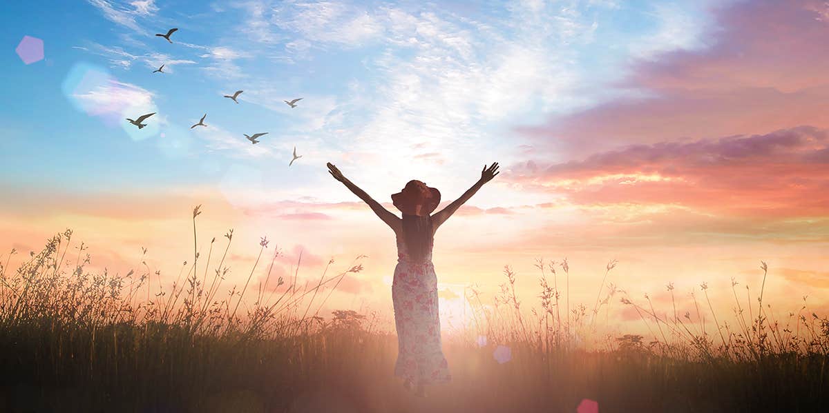 girl in sunset with arms raised