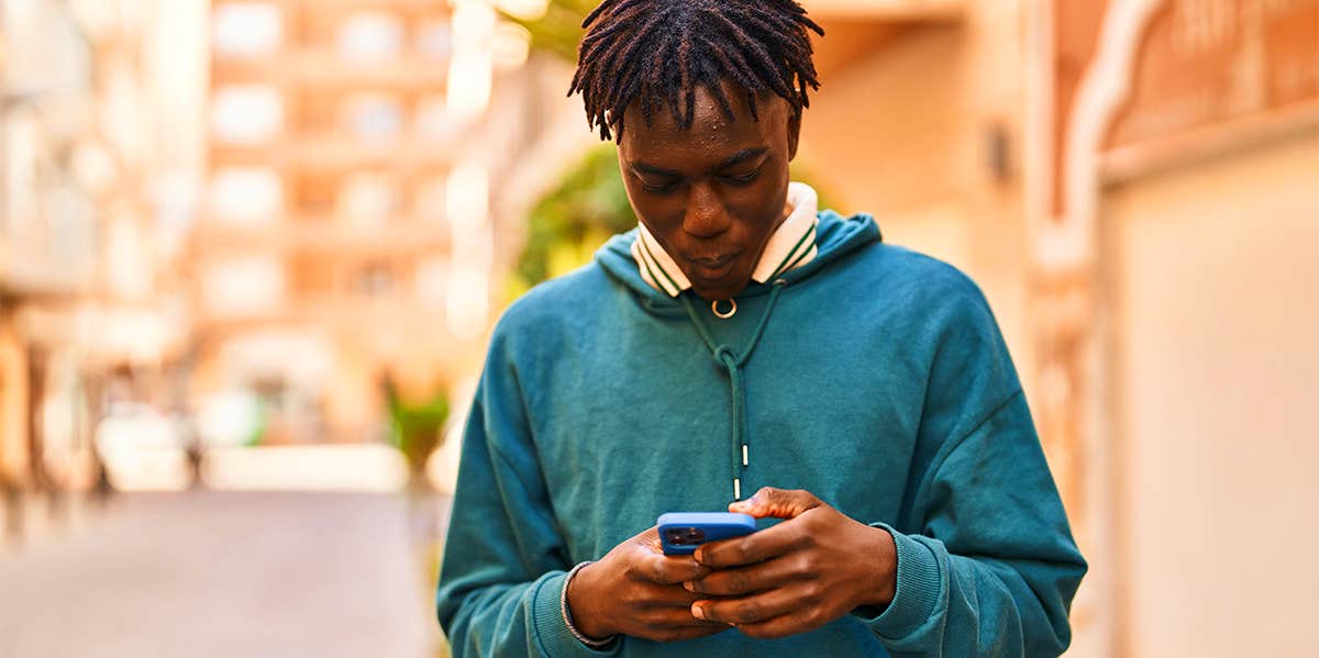 guy walking down street while texting