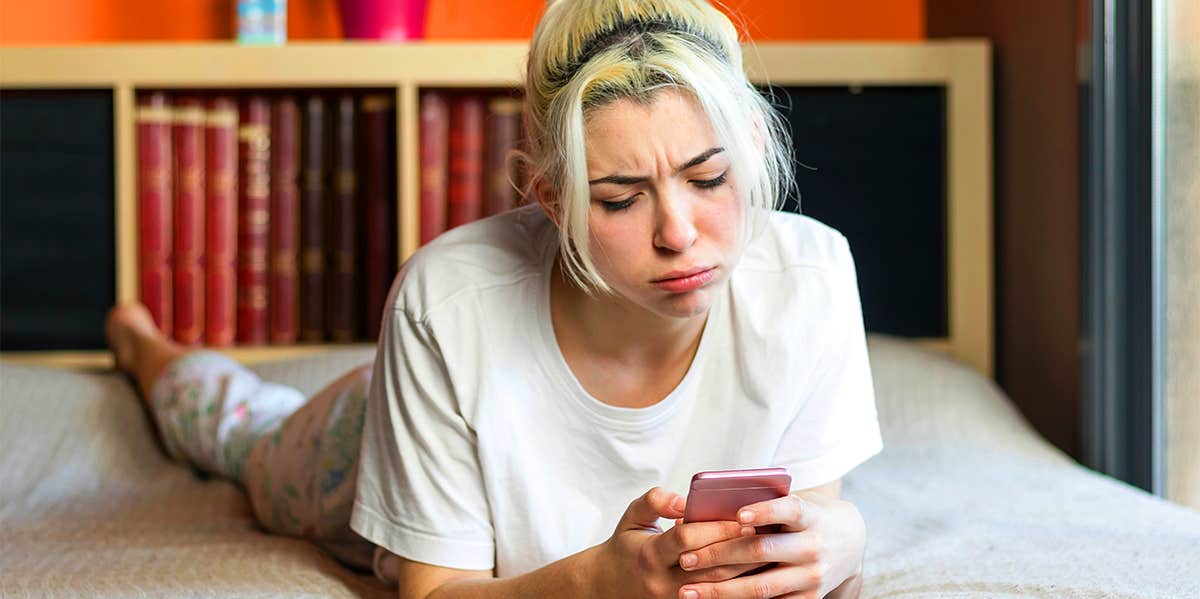 girl lying on bed looking at phone