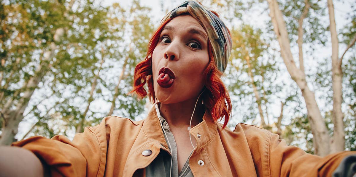 girl taking selfie making funny face sticking tongue out
