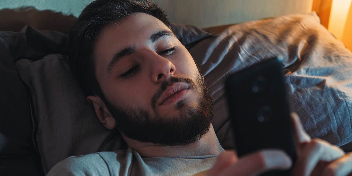 guy laying in bed looking at phone