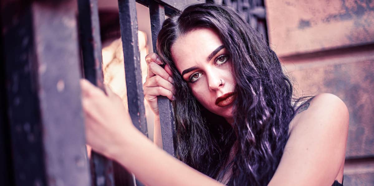 serious woman clinging onto fence
