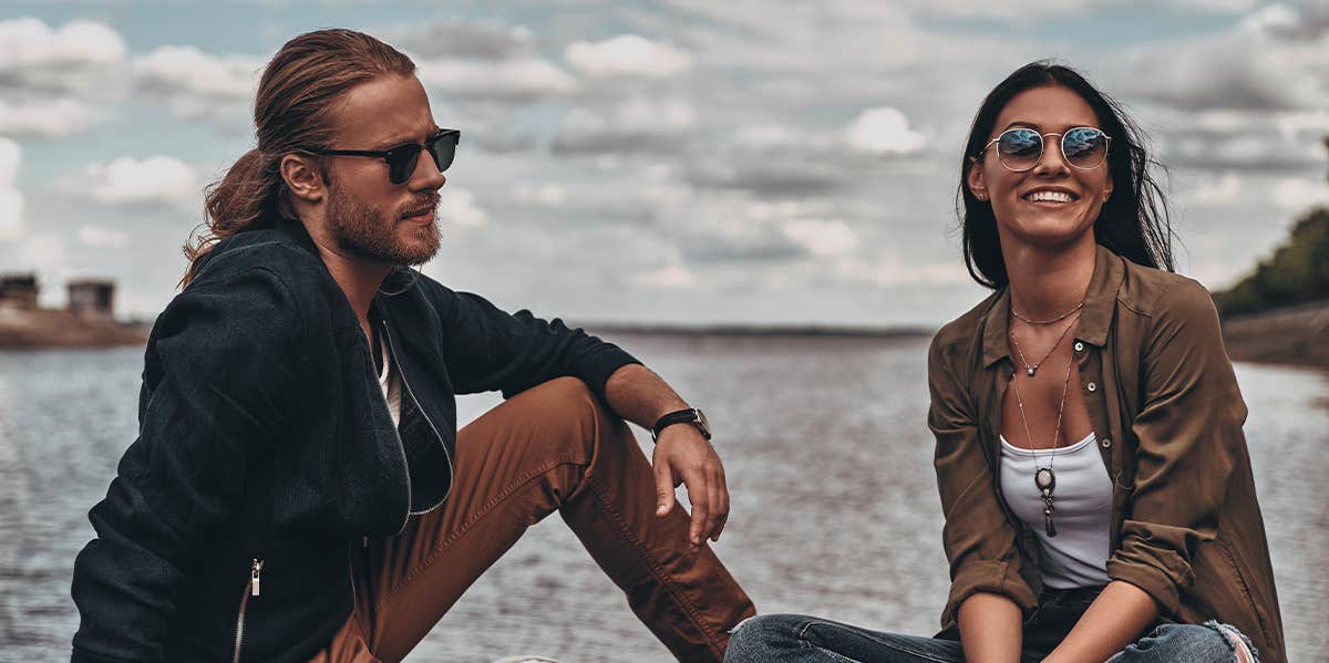 man and woman sitting by water