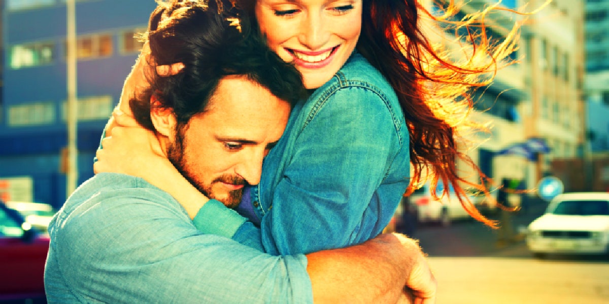 caucasian couple hugs, man serious, woman smiling