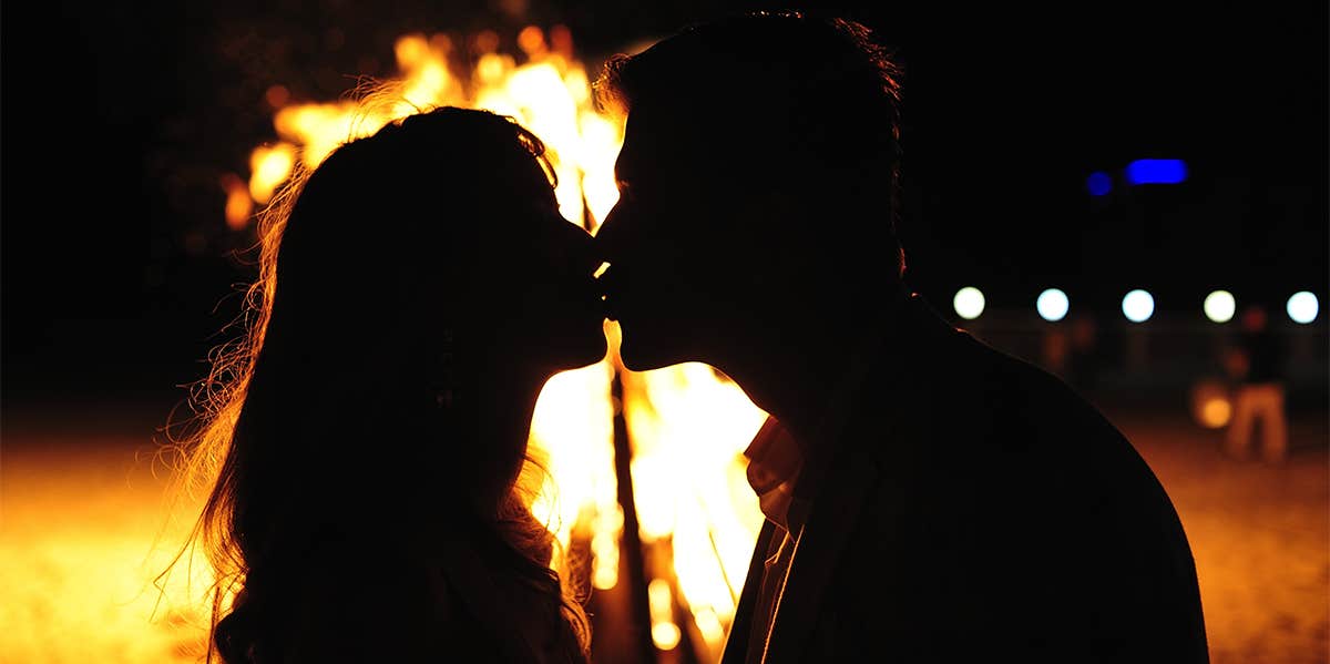 couple kissing in front of fire