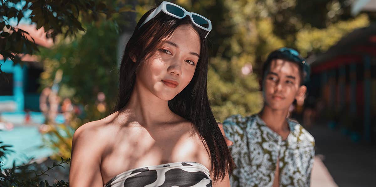 woman with sunglasses posing in summer with man behind her