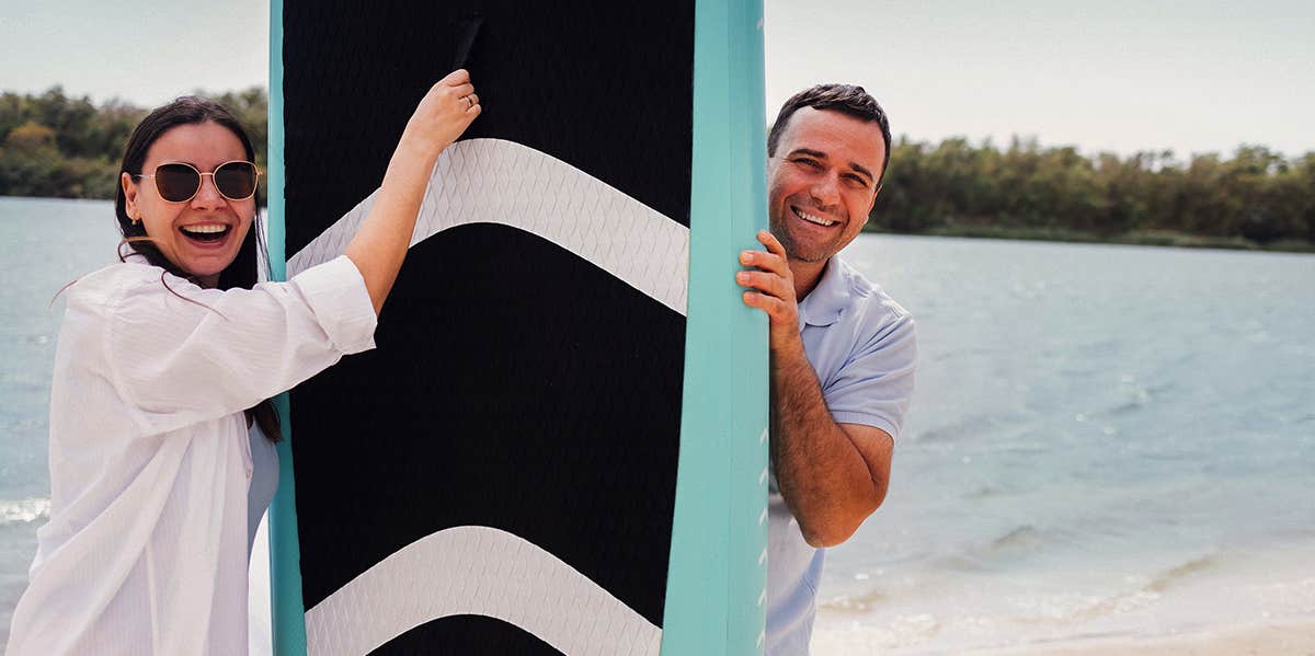 Two people holding a paddleboard 