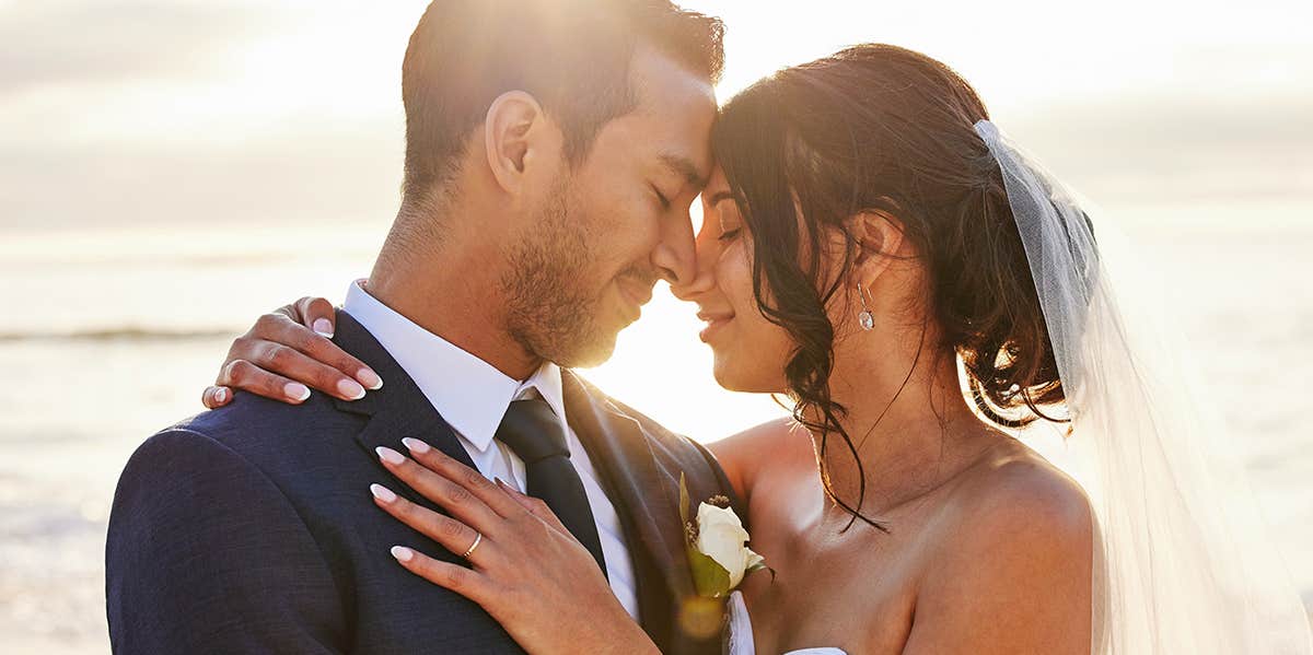 7 Easy Ways To Become The Best Damn Husband On Earth bride and groom posing together at sunset