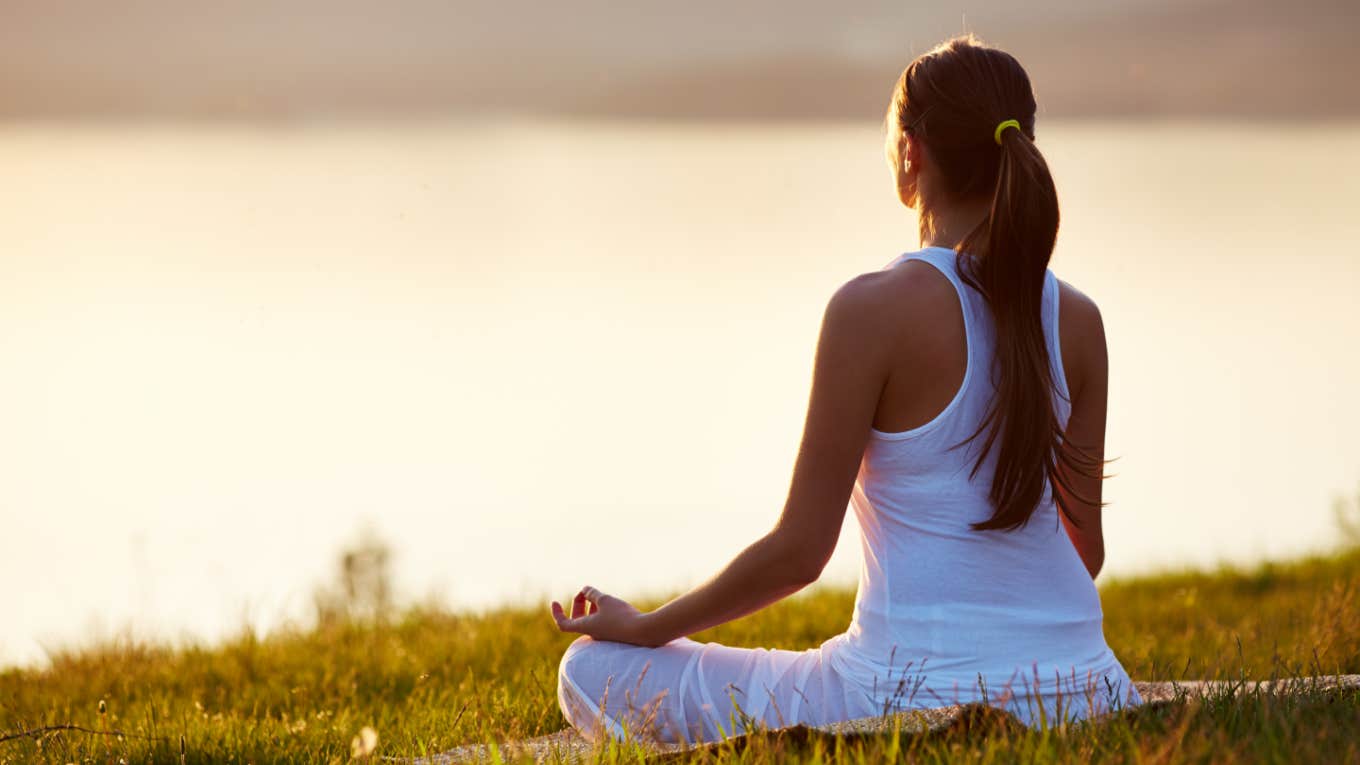 woman meditates by body of water