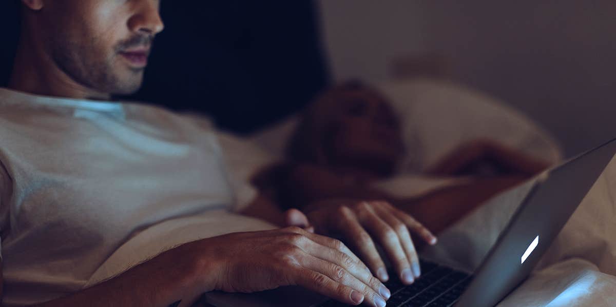 man on laptop in bed at night