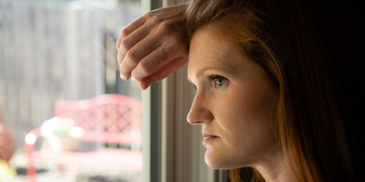Woman looks anxiously out of window