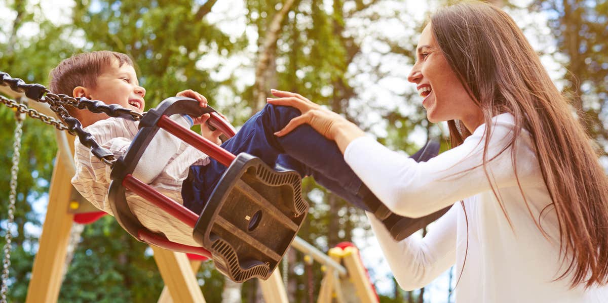 mom pushing child on swing