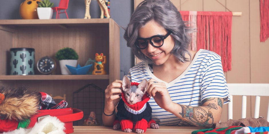 woman putting sweater on cat