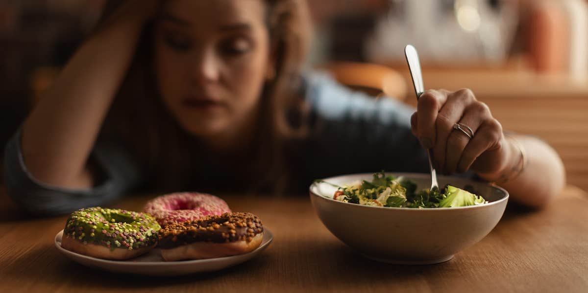 woman debating between salad or donuts