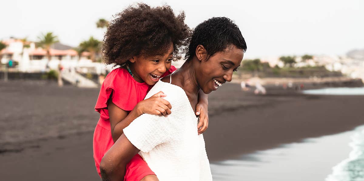 Black girl riding piggyback on back of Black boy