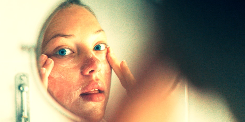 woman performing skin care routine in the mirror