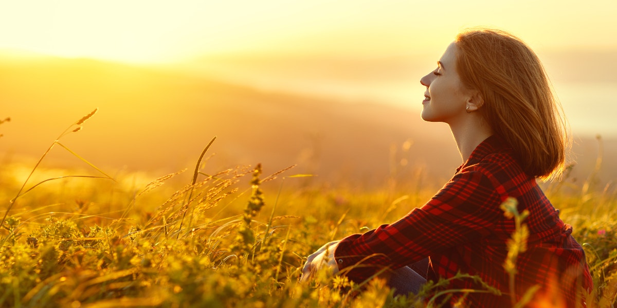 Inspired woman sitting in field