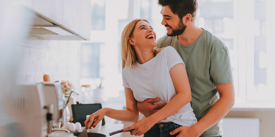 man embracing woman by the waist in kitchen