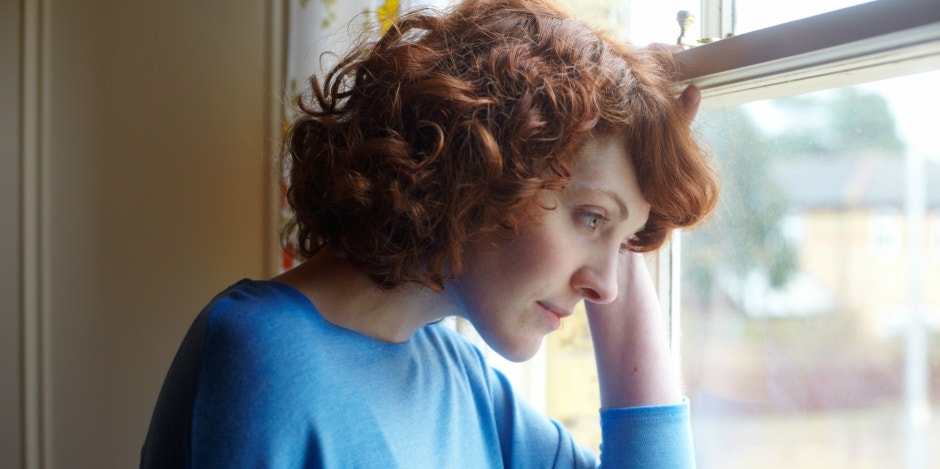 woman looking forlorn next to window