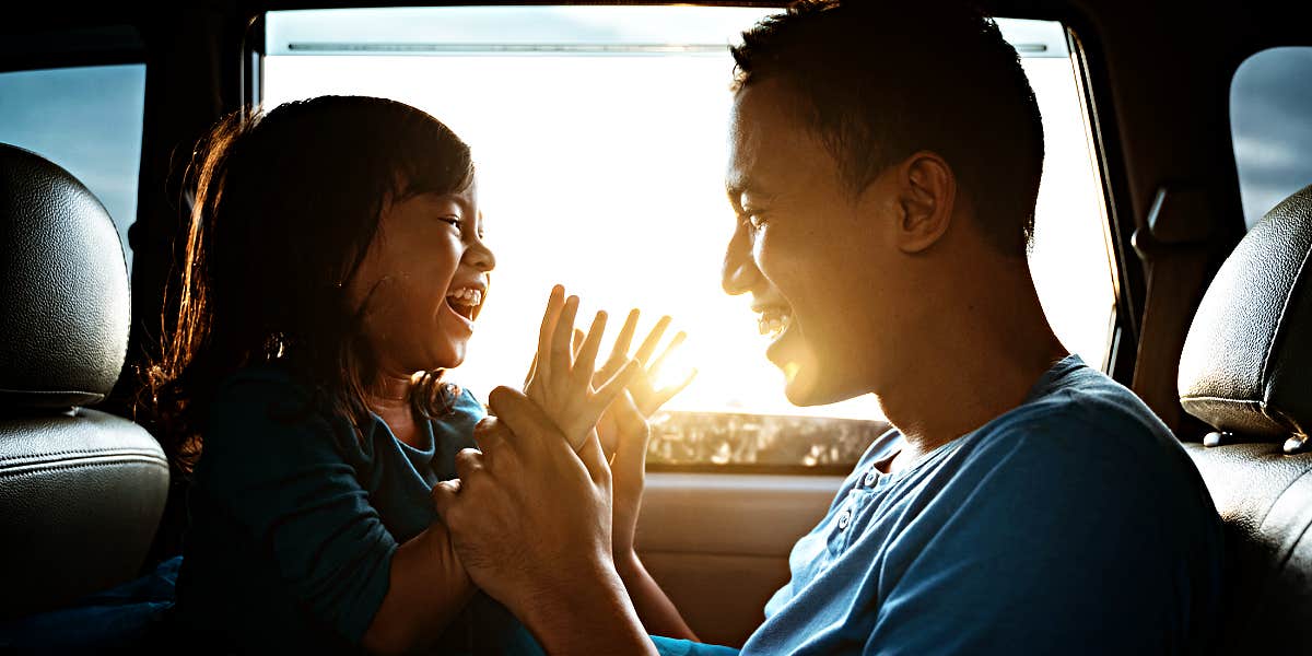 How to show kids you adore them Asian father playing with his daughter in a car, boy laughing, backlit