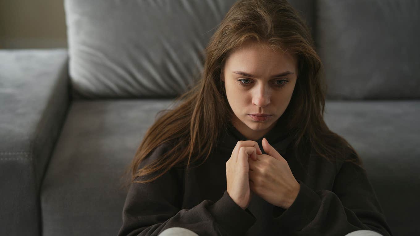 Caucasian nervous woman sitting at the couch in home