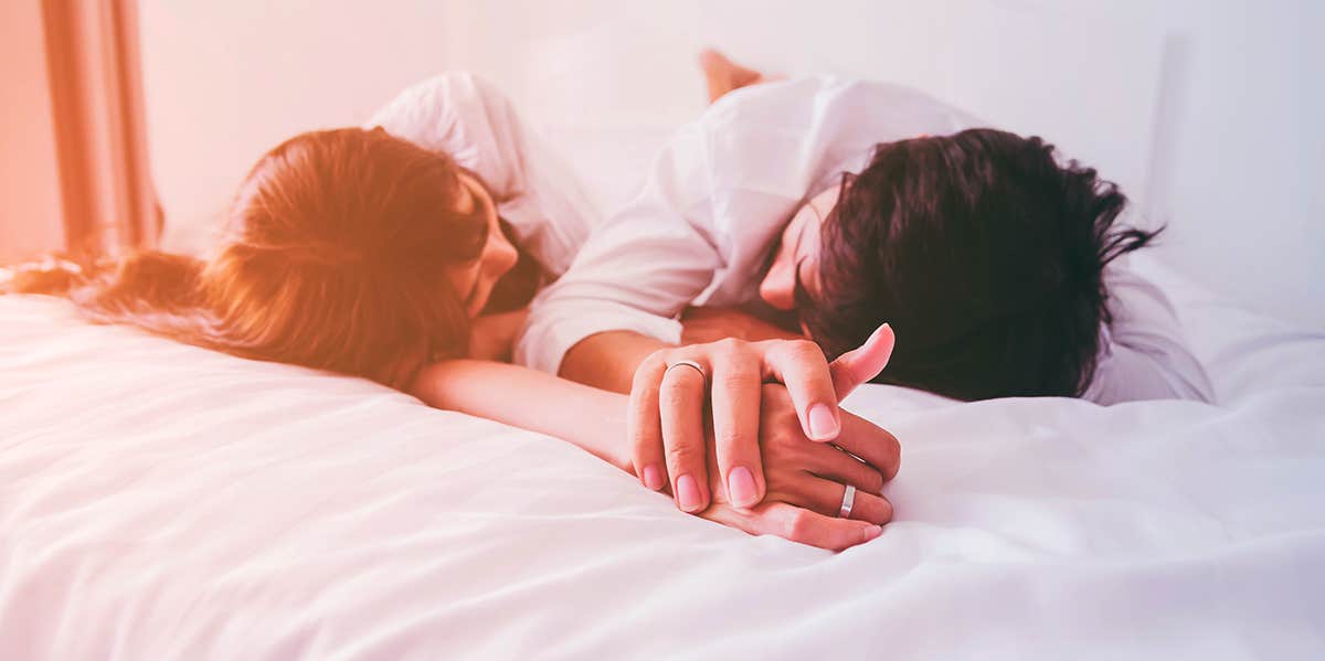 Couple lying in bed holding hands