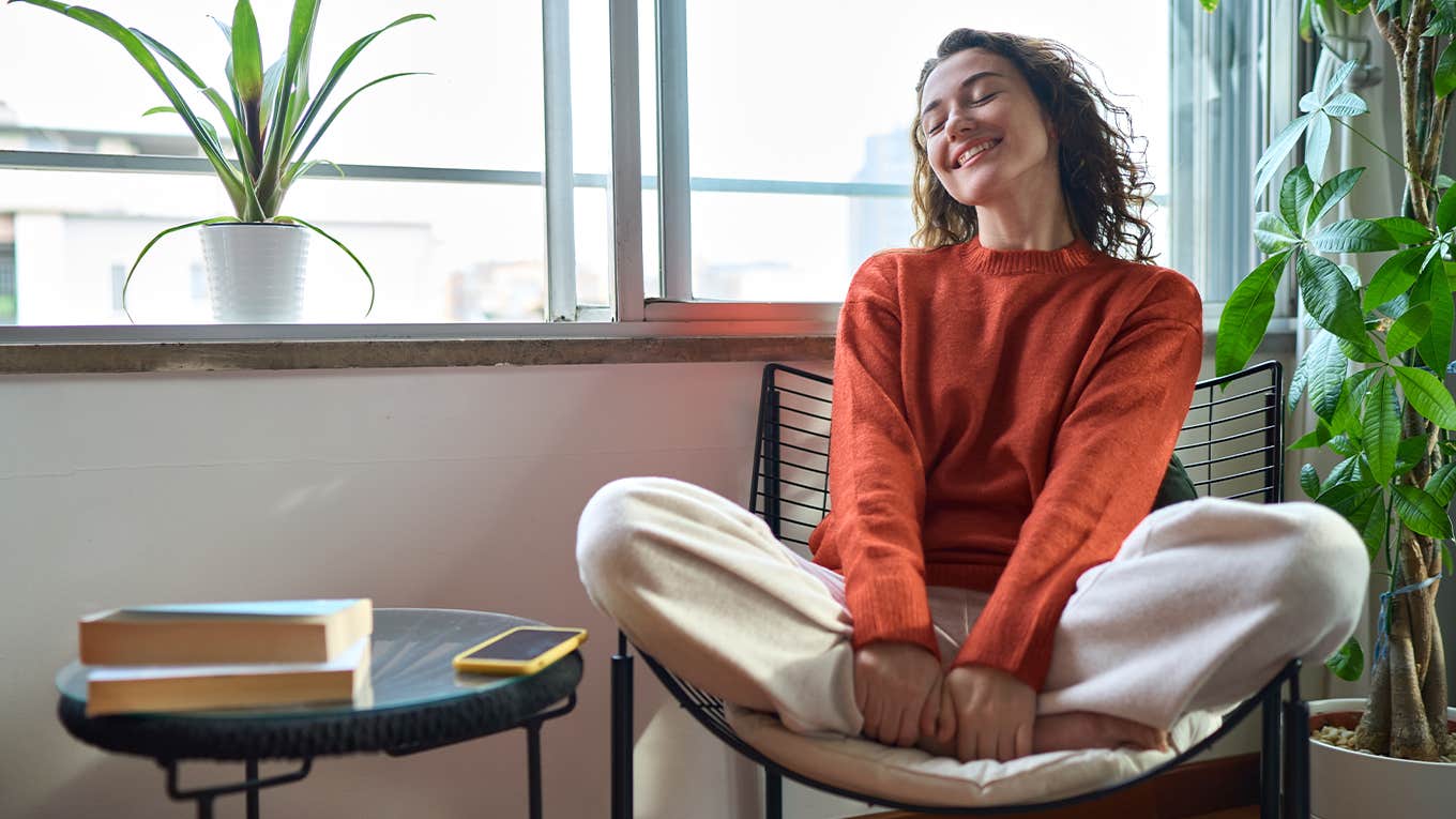 Young relaxed smiling pretty woman relaxing sitting on chair at home.