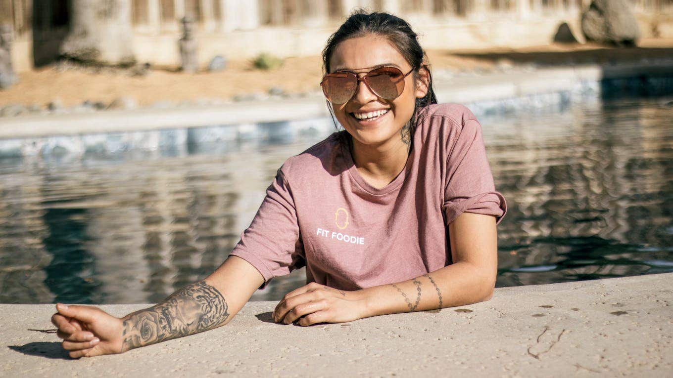 Cheerful brunette with tattoo Woman in pool showing off tattoo