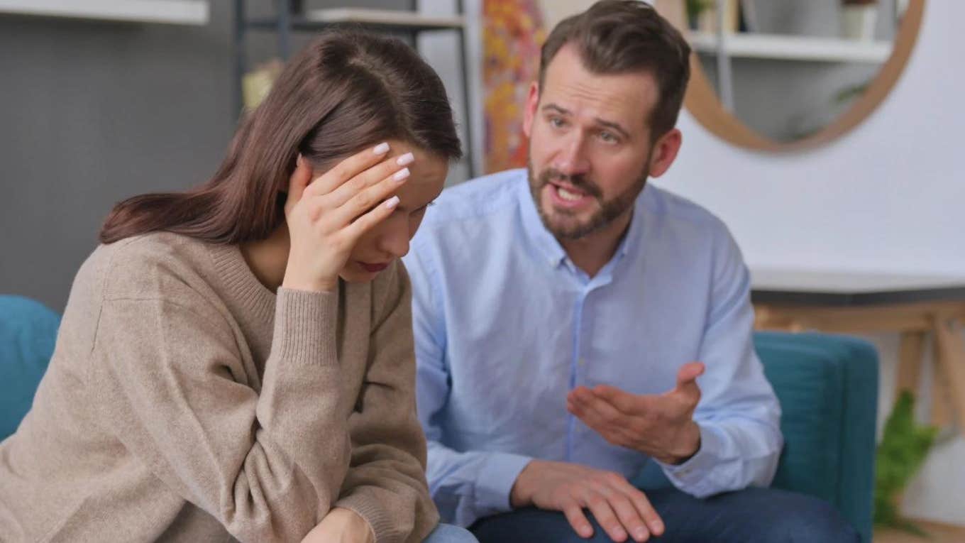 man arguing with woman while she holds her head