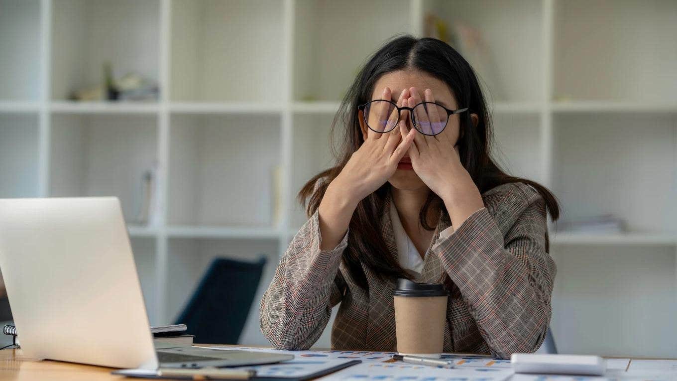 woman at work holding head in hands