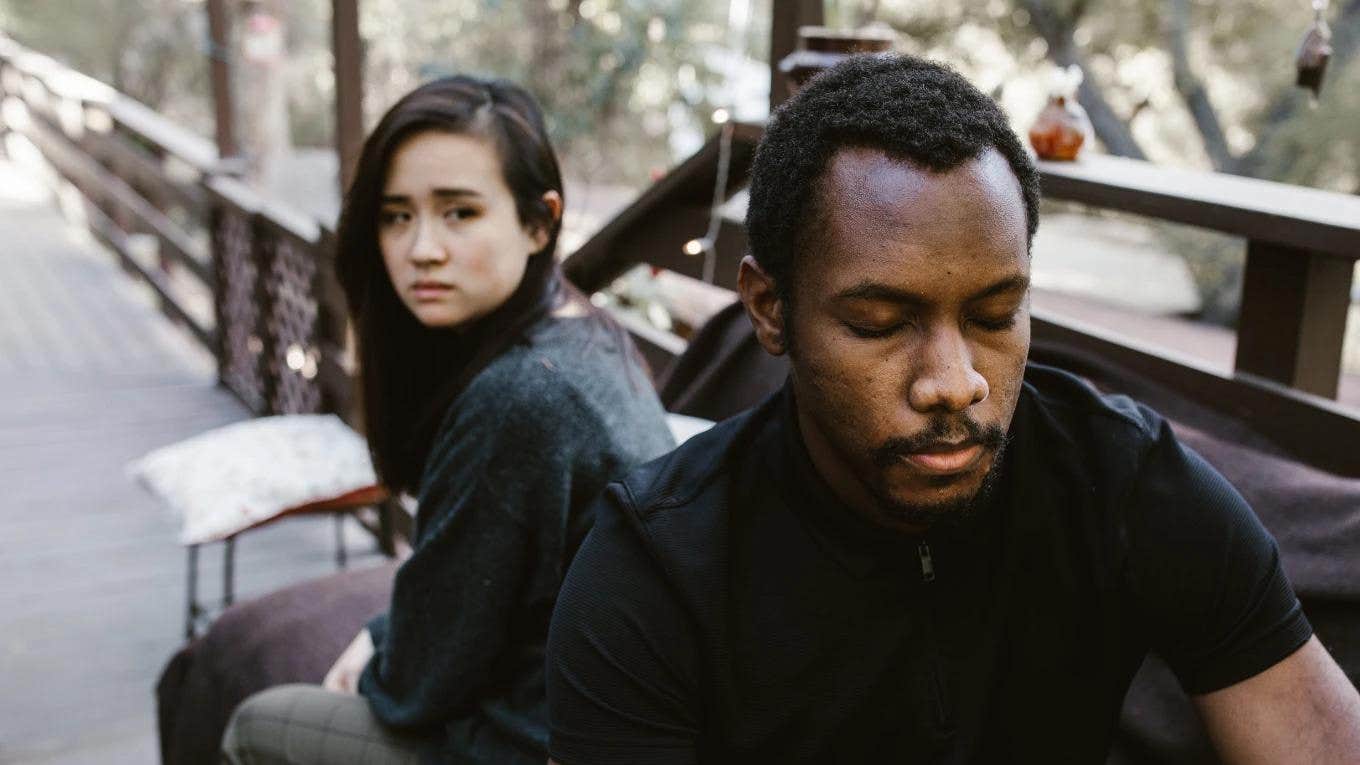 man in woman sitting on a bench looking sad