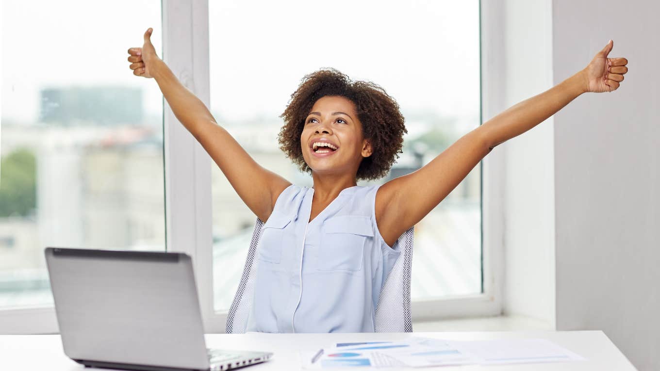 Woman Says She Found A Lazy Girl Job Sent From Heaven woman celebrating at work with arms raised