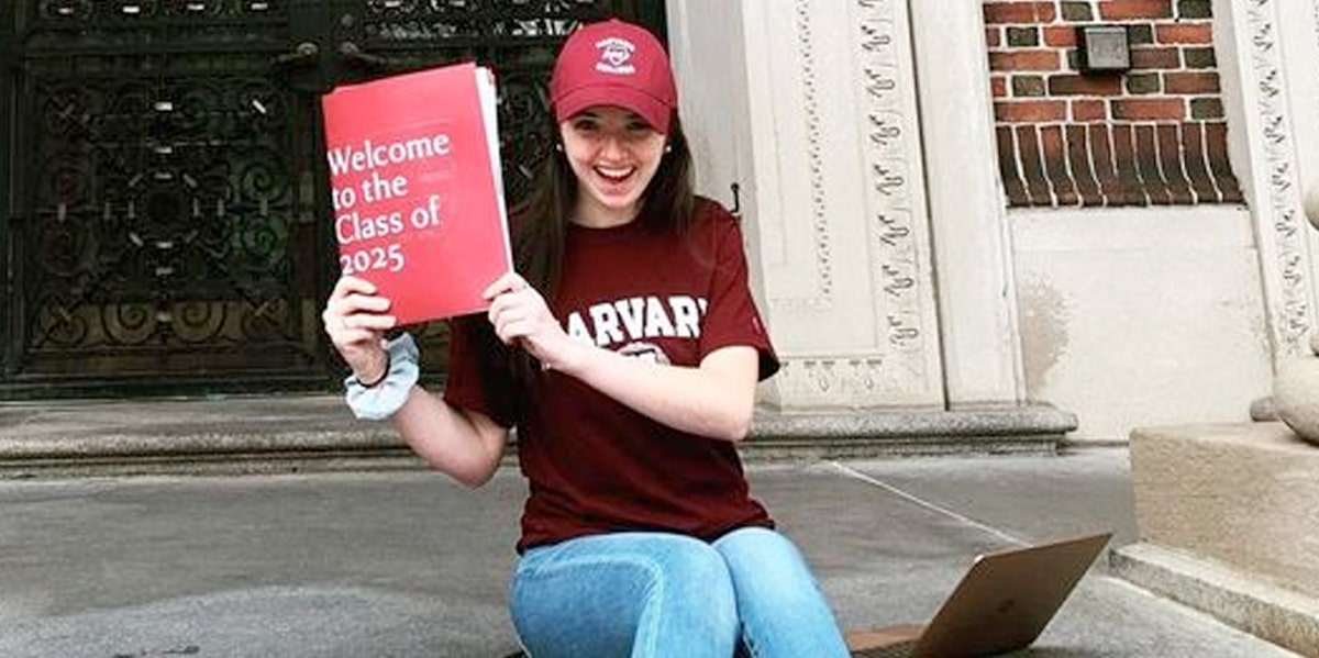 Abigail Mack wearing some Harvard merch and posing with an acceptance folder from the university.