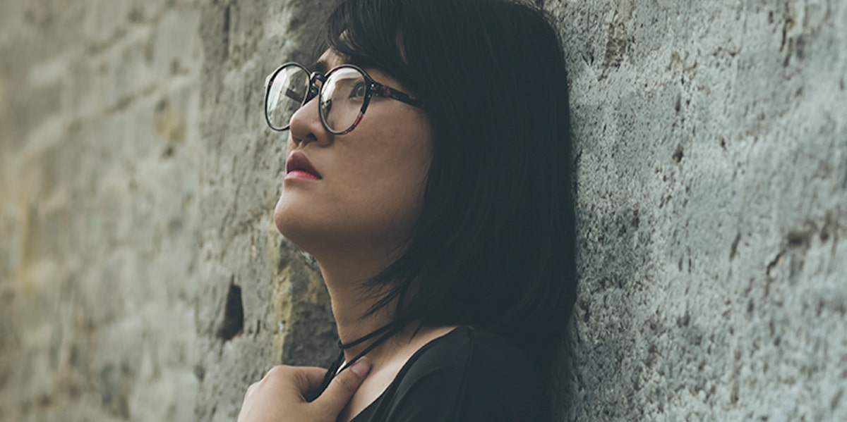 woman looking sad leaning against brick wall