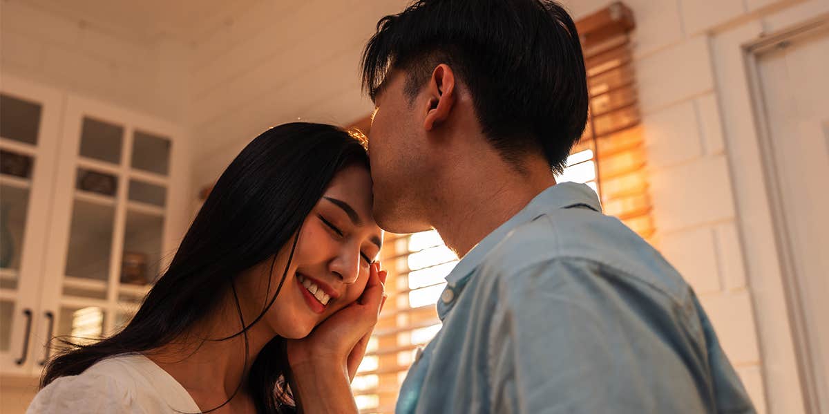 man kissing woman's forehead