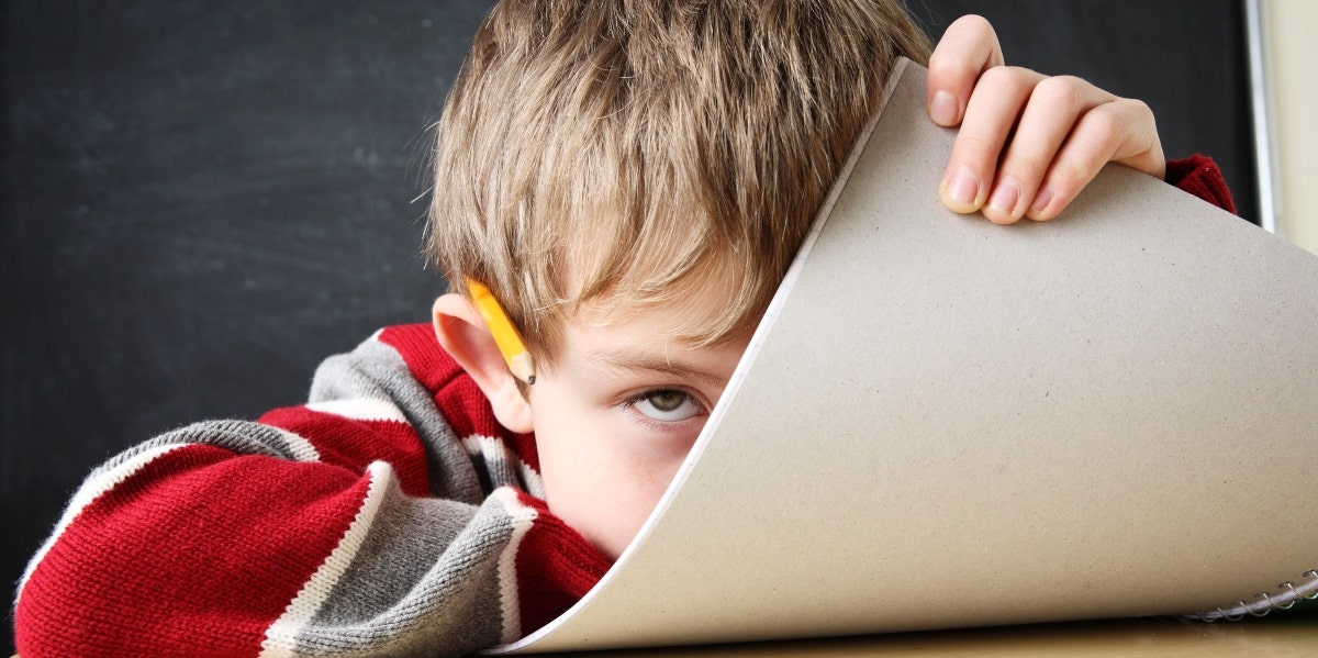 adhd and school boy hiding behind paper