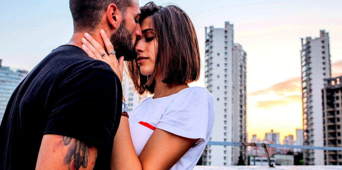 man kissing woman on forehead