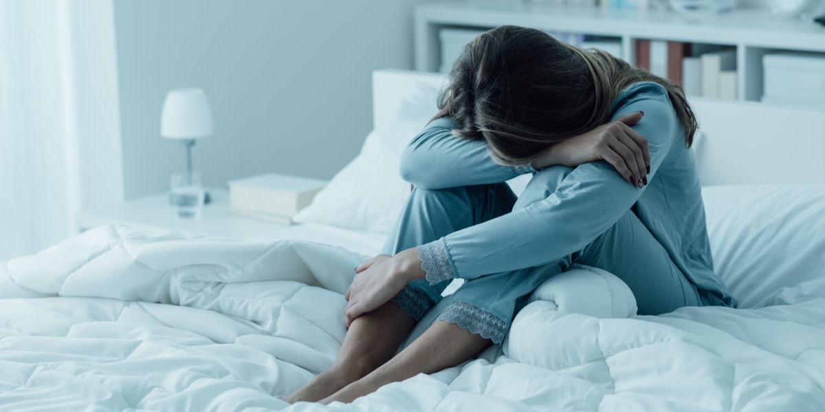 woman on bed with head in hands