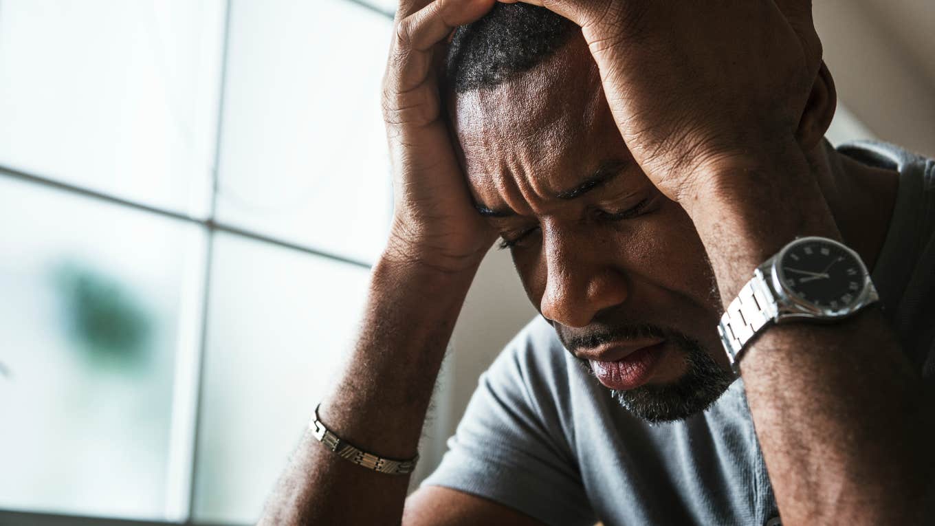 close-up shot of upset man holding his head in his hands