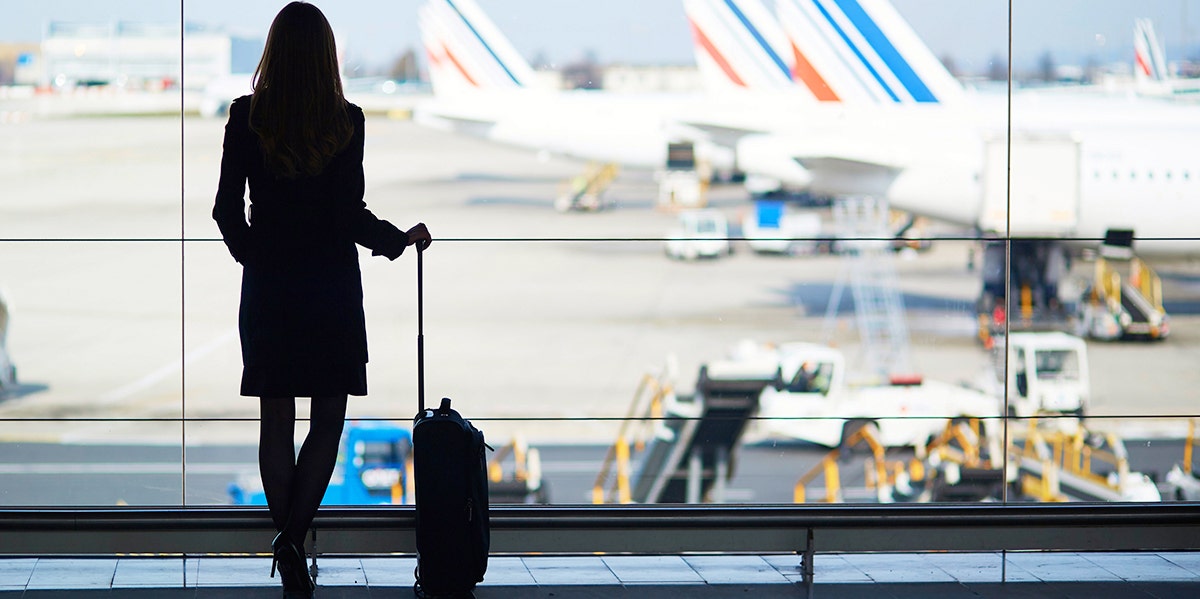 woman with luggage looking at airplanes