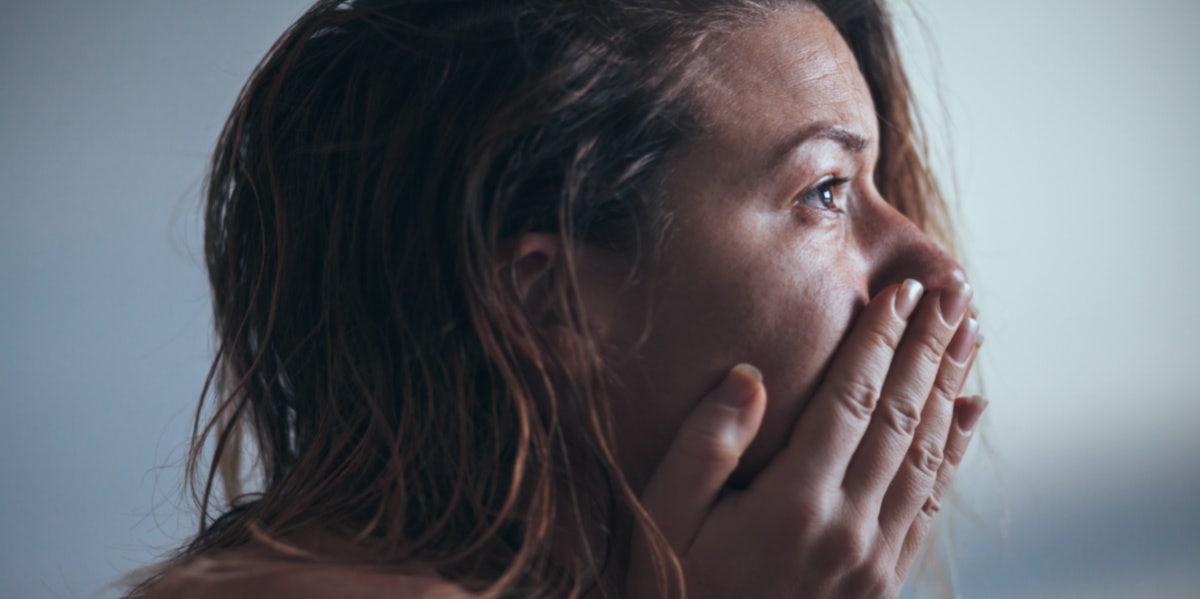 sad woman looking forward hands over face